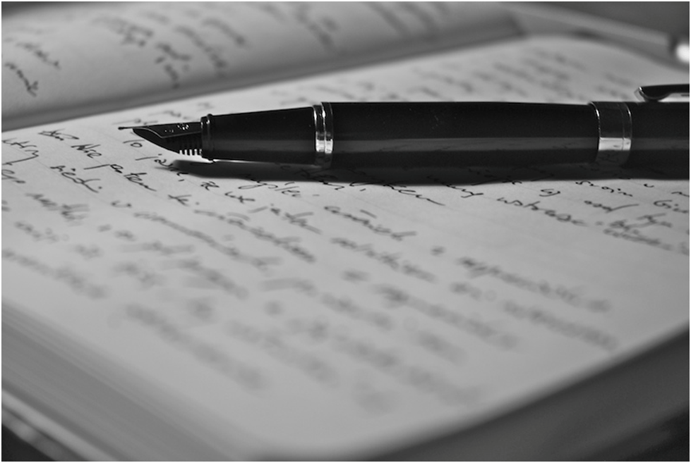 Fountain pen on open journal with handwriting on it